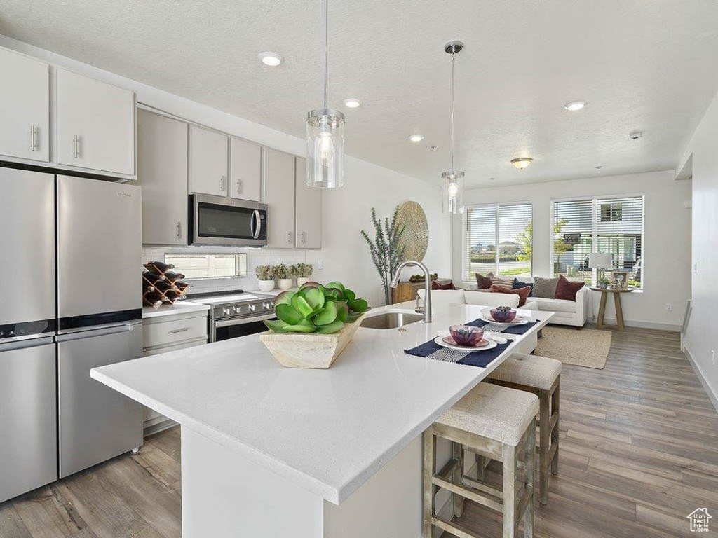 Kitchen featuring stainless steel appliances, light countertops, light wood finished floors, recessed lighting, and a textured ceiling
