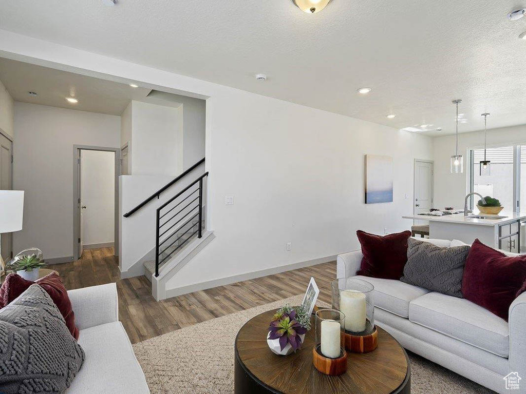 Living room featuring wood finished floors, stairway, recessed lighting, and a textured ceiling