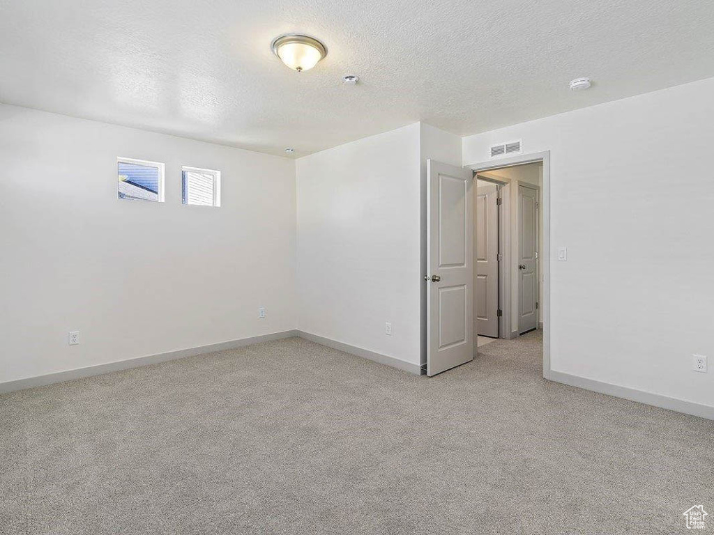 Spare room featuring light carpet, a textured ceiling, and fire sprinkler in ceiling