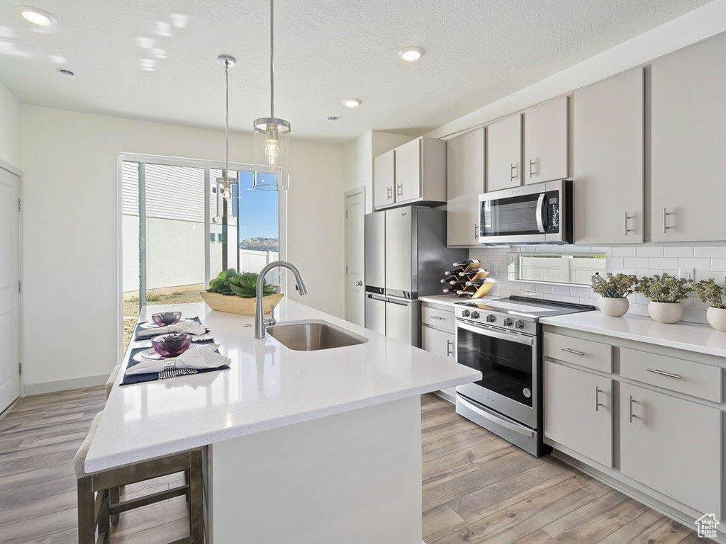Kitchen featuring appliances with stainless steel finishes, backsplash, light wood finished floors, light countertops, and recessed lighting