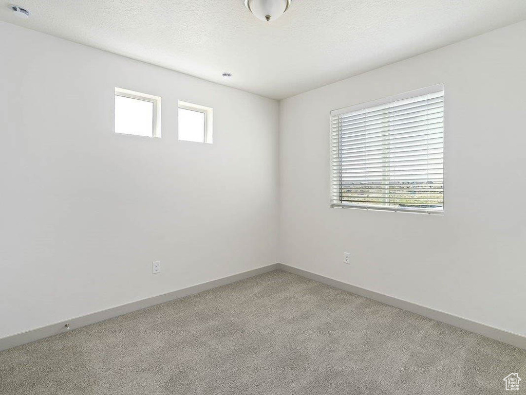 Spare room featuring light colored carpet and a textured ceiling