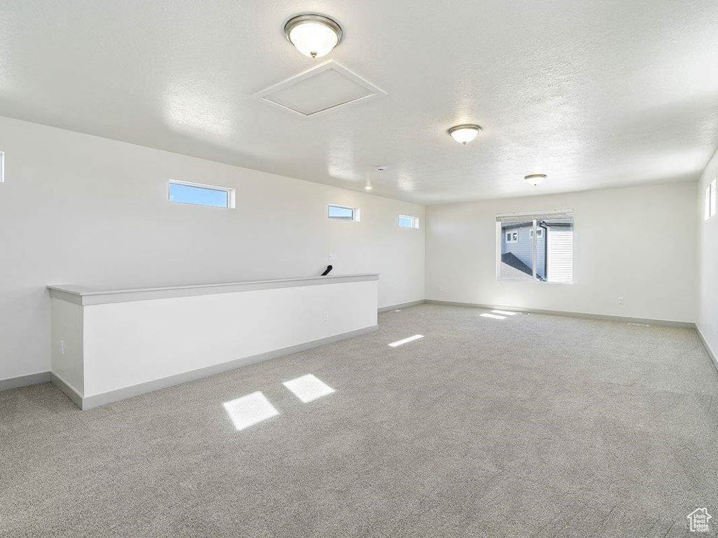 Empty room with light carpet, plenty of natural light, and a textured ceiling