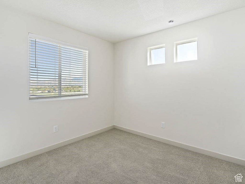 Empty room with light colored carpet and a textured ceiling