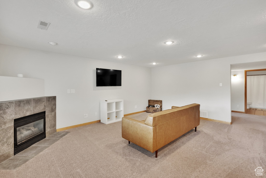 Living area with light colored carpet, a tile fireplace, a textured ceiling, and recessed lighting
