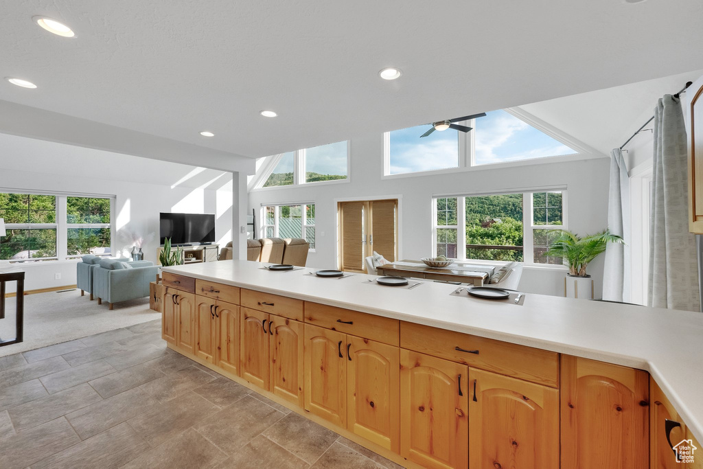 Kitchen with open floor plan, ceiling fan, vaulted ceiling, light countertops, and recessed lighting