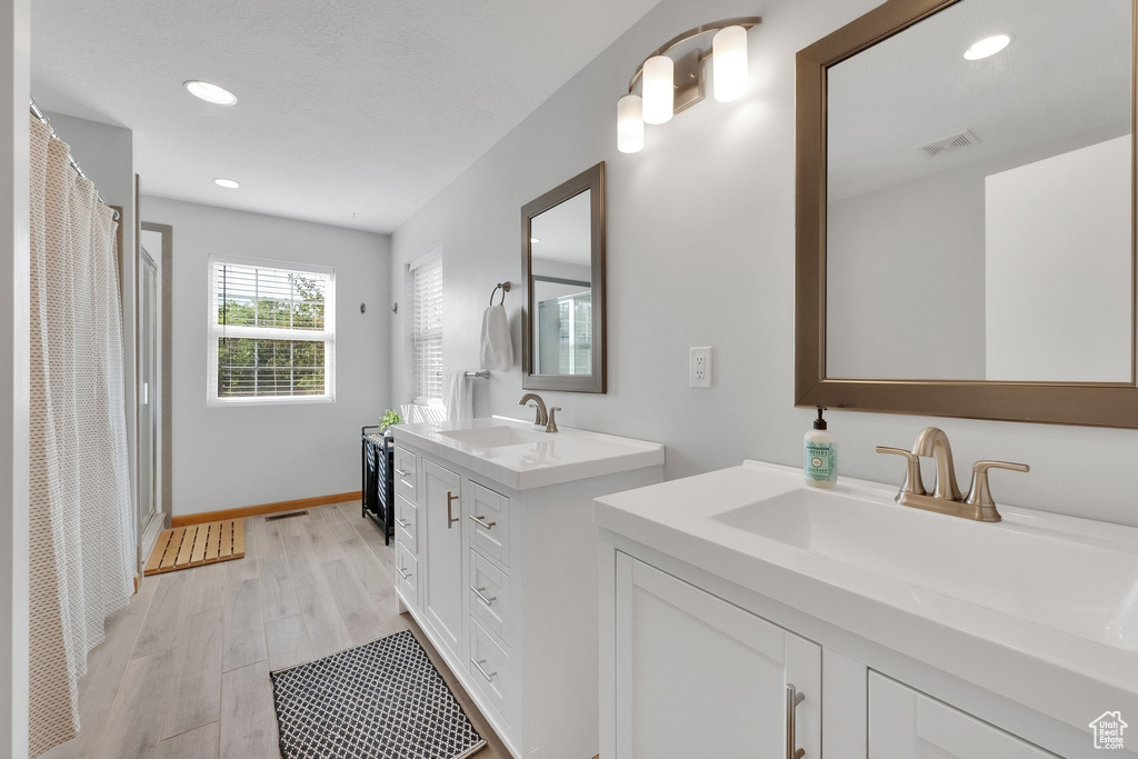 Bathroom with two vanities, wood finished floors, recessed lighting, and curtained shower