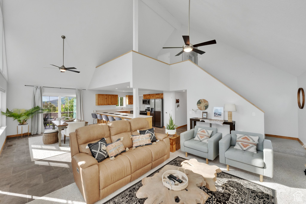 Living room featuring a ceiling fan, high vaulted ceiling, and beam ceiling