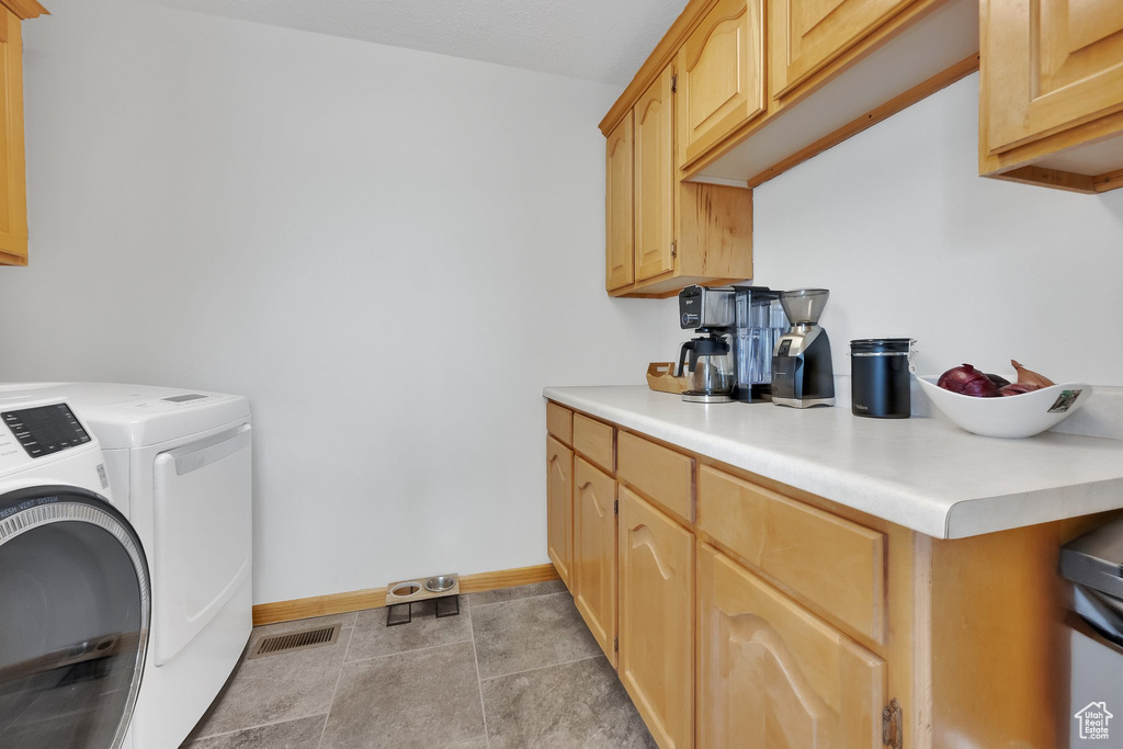 Washroom featuring washer and dryer and light tile patterned floors
