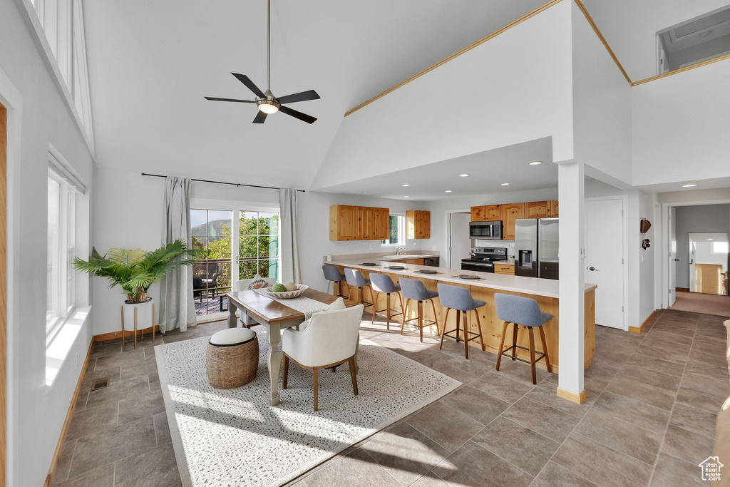 Dining room with high vaulted ceiling, a ceiling fan, light stone finish flooring, and recessed lighting