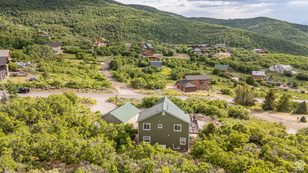 Aerial view of property and surrounding area with a mountain backdrop and a heavily wooded area