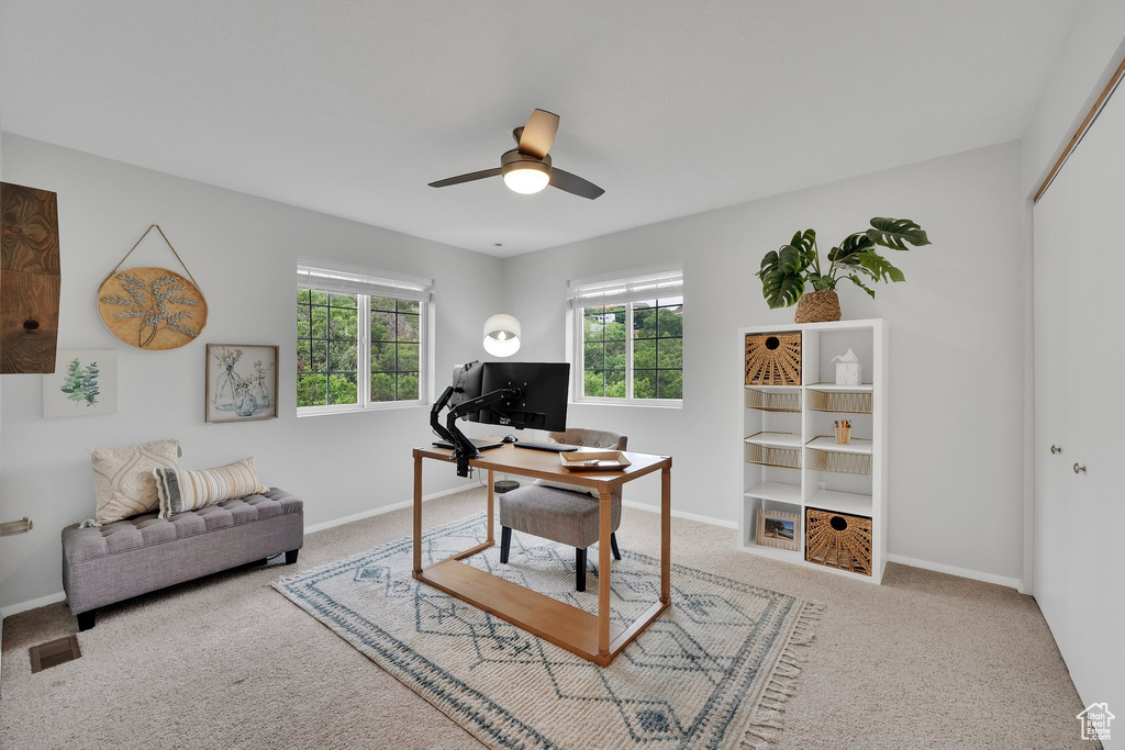 Carpeted office space with a ceiling fan and baseboards