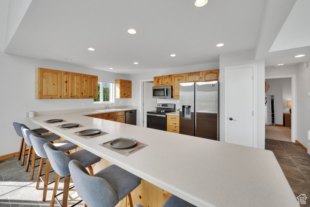 Kitchen featuring appliances with stainless steel finishes, recessed lighting, a breakfast bar area, light countertops, and a peninsula