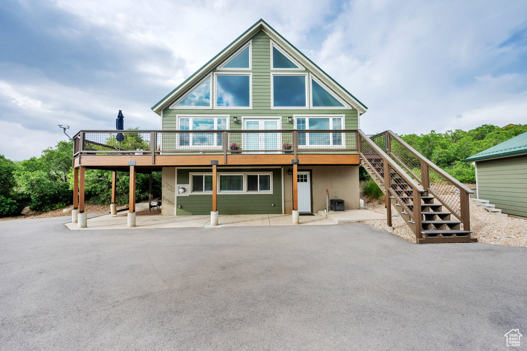 View of front of house with stairs, a deck, and a patio area