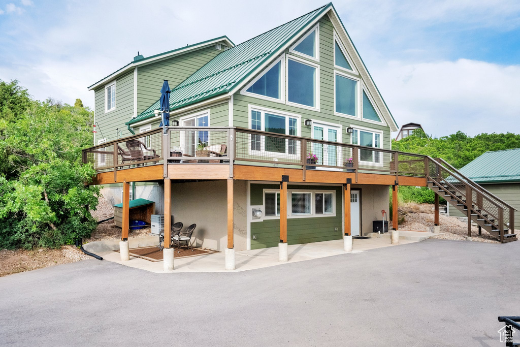 Rear view of house featuring stairs, a patio area, a wooden deck, and a metal roof