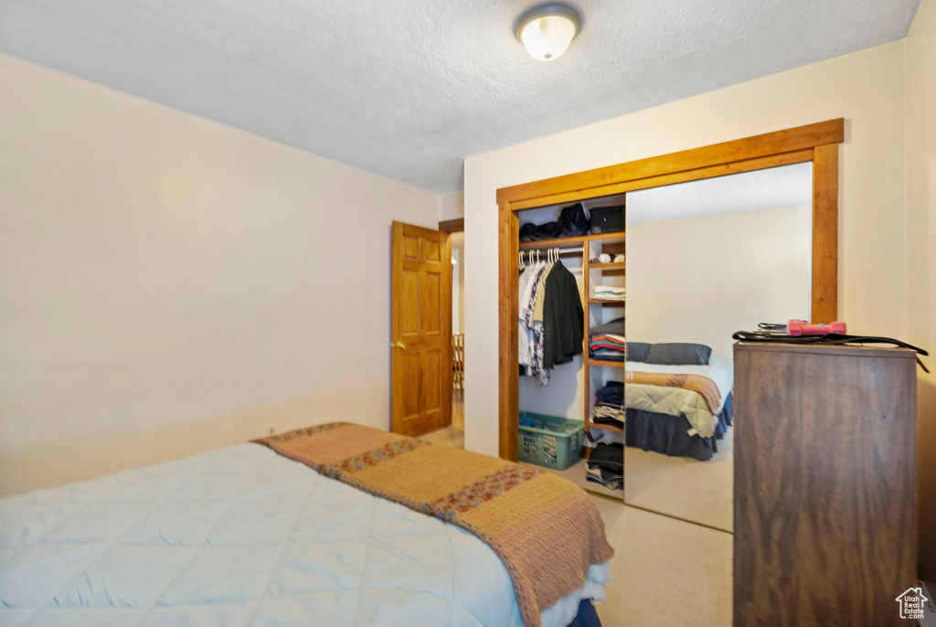 Carpeted bedroom featuring a textured ceiling and a closet
