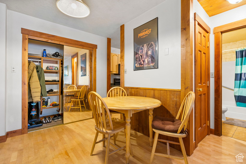 Dining space featuring wainscoting, light wood-type flooring, and wood walls