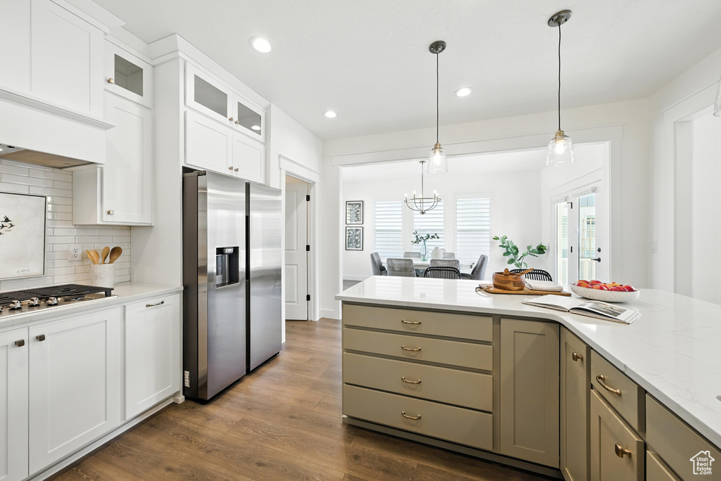 Kitchen featuring stainless steel appliances, decorative backsplash, glass insert cabinets, pendant lighting, and dark wood finished floors