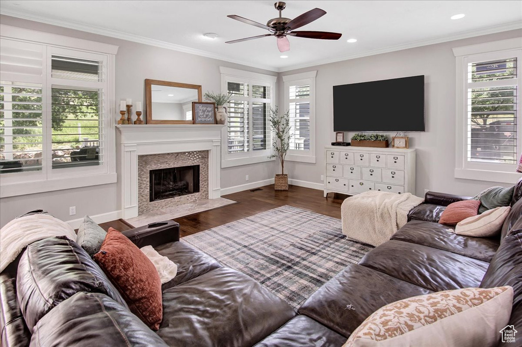 Living area with ceiling fan, wood finished floors, a premium fireplace, recessed lighting, and ornamental molding