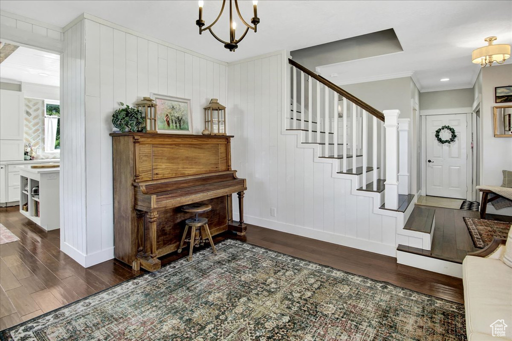 Foyer featuring dark wood-style floors, a chandelier, crown molding, and stairway