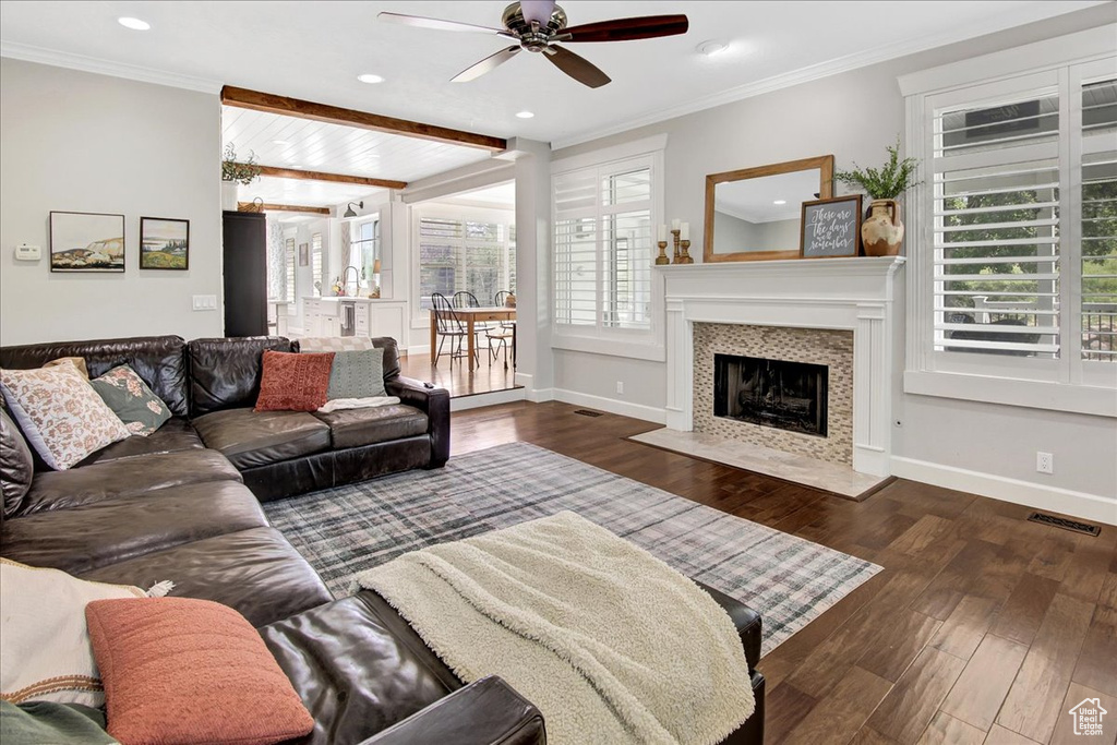 Living area featuring ceiling fan, wood finished floors, recessed lighting, a tiled fireplace, and crown molding