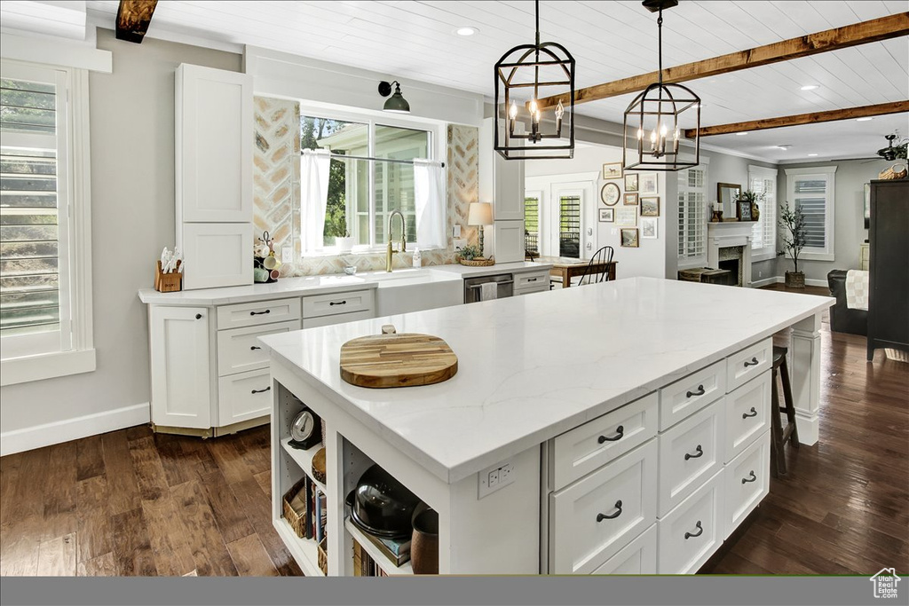 Kitchen featuring a kitchen island, a wood ceiling with exposed beams, plenty of natural light, white cabinetry, and dark wood finished floors