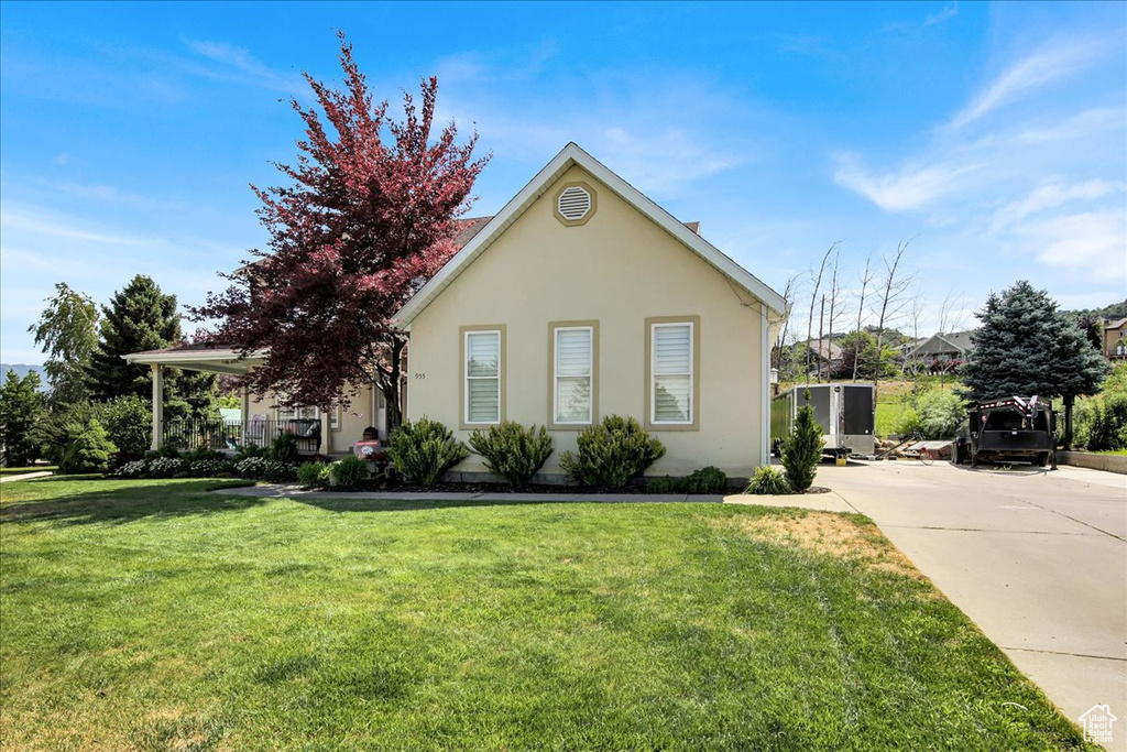 View of front of property with a front yard, stucco siding, and driveway