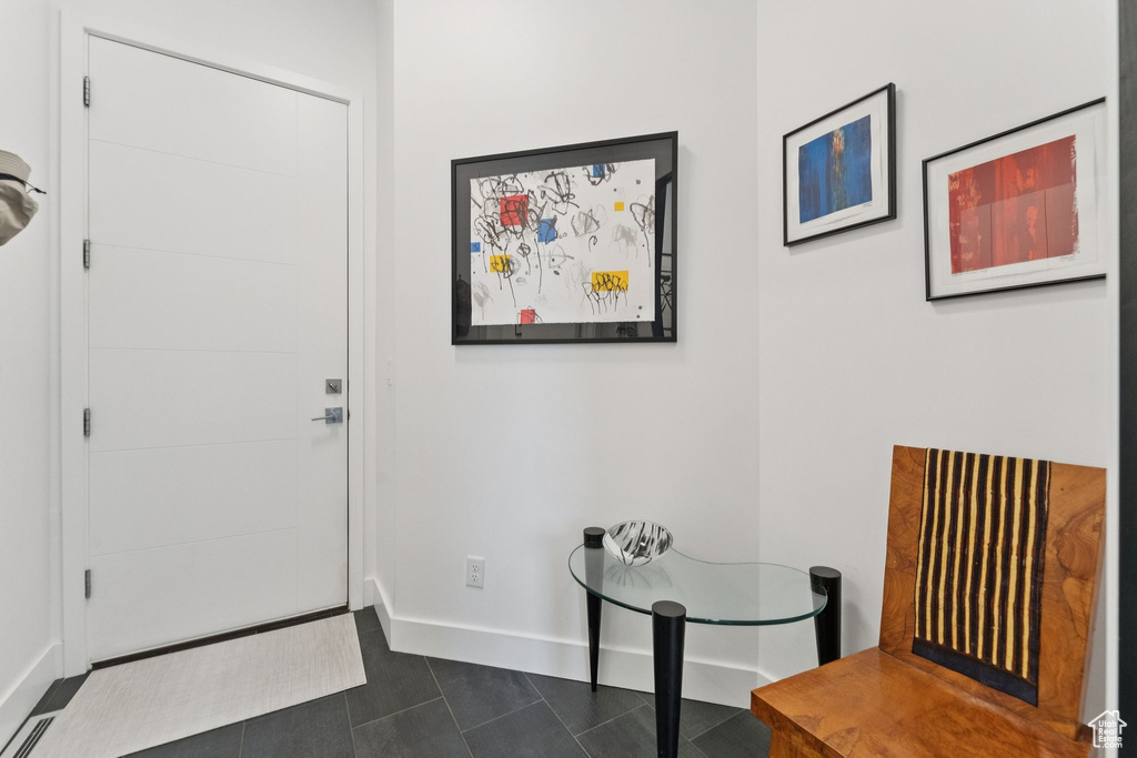 Foyer entrance featuring baseboards and dark tile patterned floors