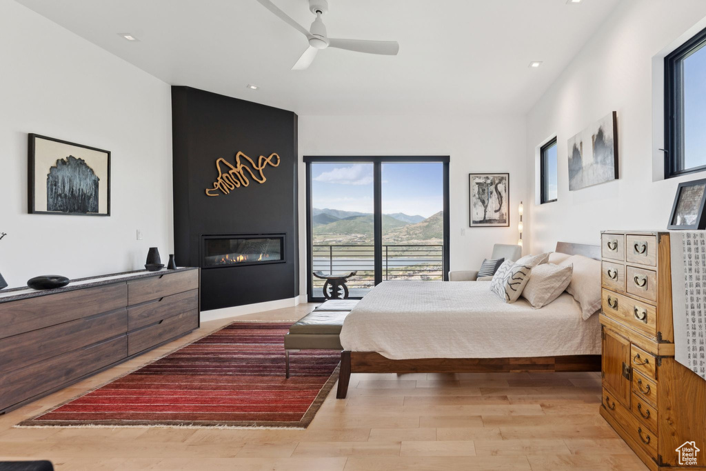 Bedroom featuring a mountain view, light wood-style floors, a large fireplace, access to exterior, and recessed lighting
