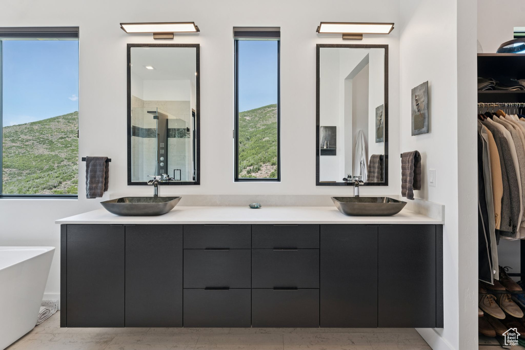 Bathroom with a shower stall, double vanity, a walk in closet, and a soaking tub