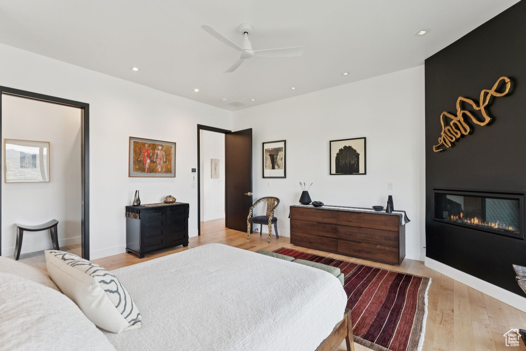 Bedroom with light wood finished floors, a large fireplace, ceiling fan, and recessed lighting