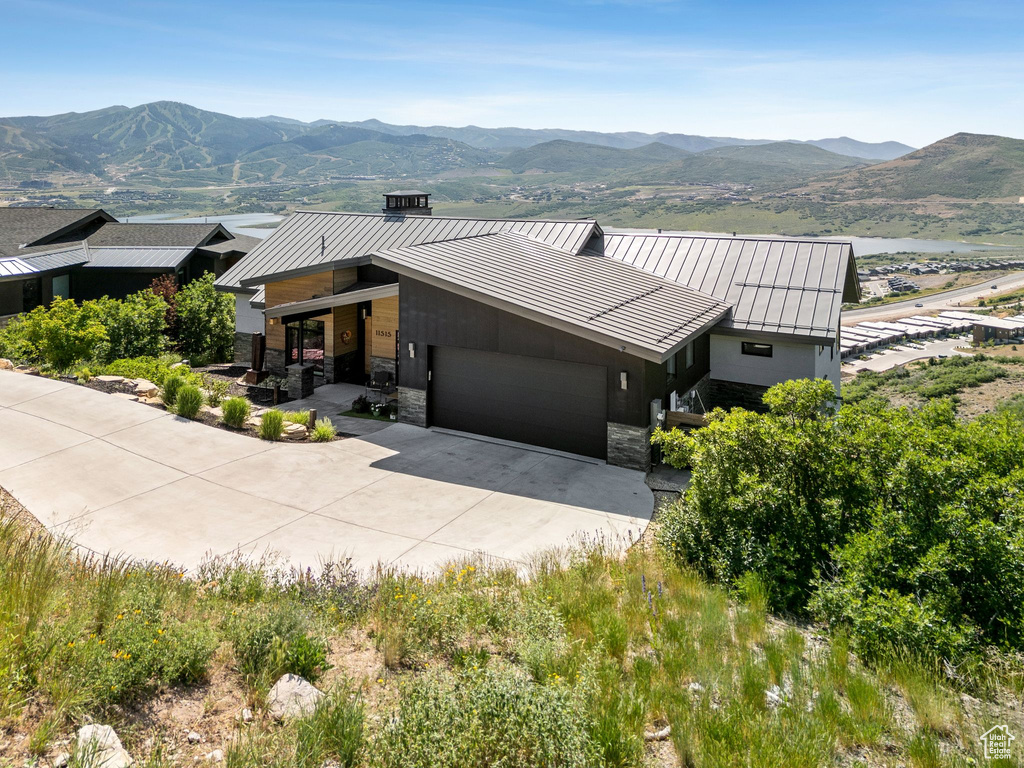 View of front of house with a standing seam roof, a garage, a mountain view, driveway, and a metal roof