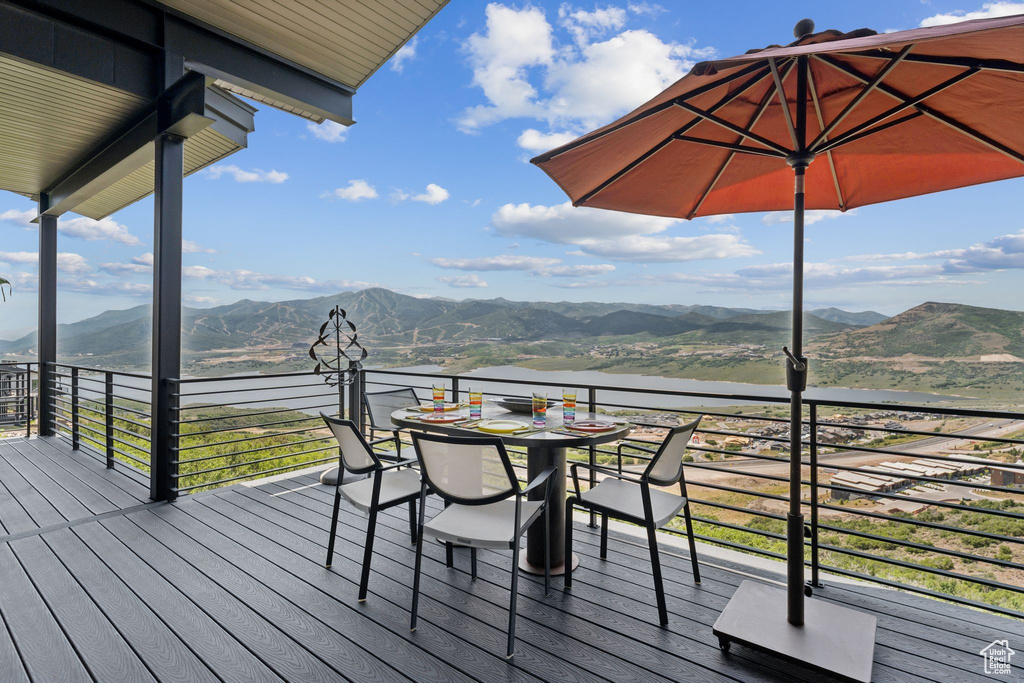 Deck with a water and mountain view and outdoor dining space