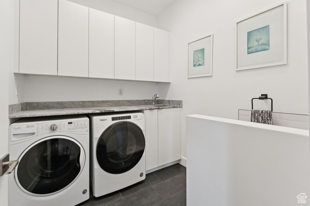 Laundry area featuring separate washer and dryer, cabinet space, and dark tile patterned floors