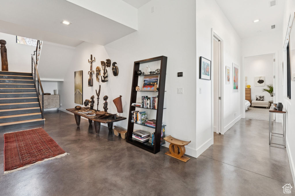 Corridor with finished concrete floors, stairs, and recessed lighting