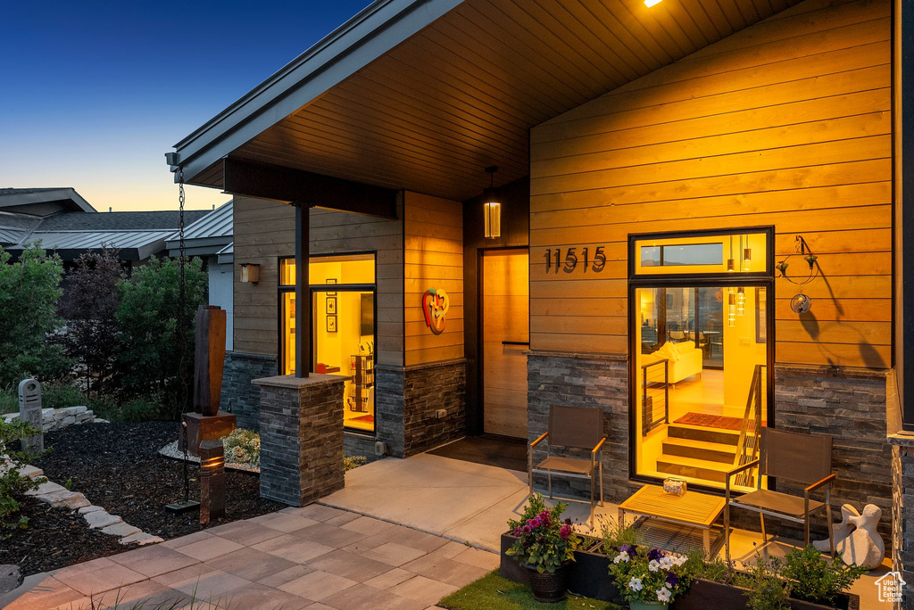 Doorway to property featuring stone siding and covered porch