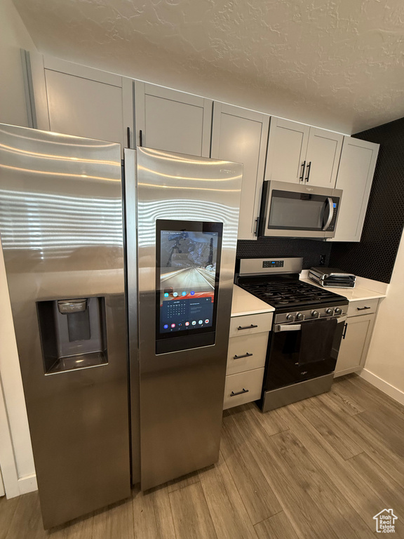 Kitchen featuring stainless steel appliances, light wood finished floors, light countertops, and a textured ceiling