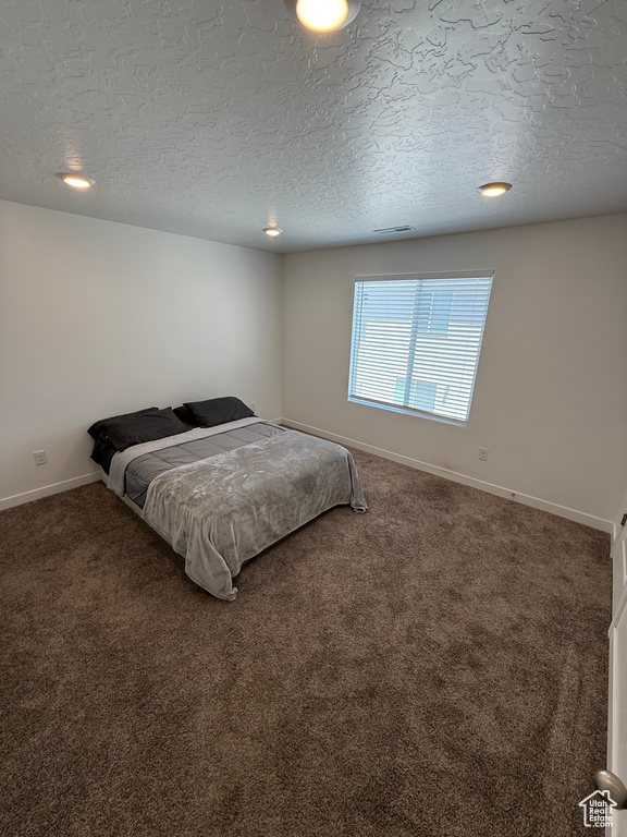 Carpeted bedroom featuring a textured ceiling and recessed lighting