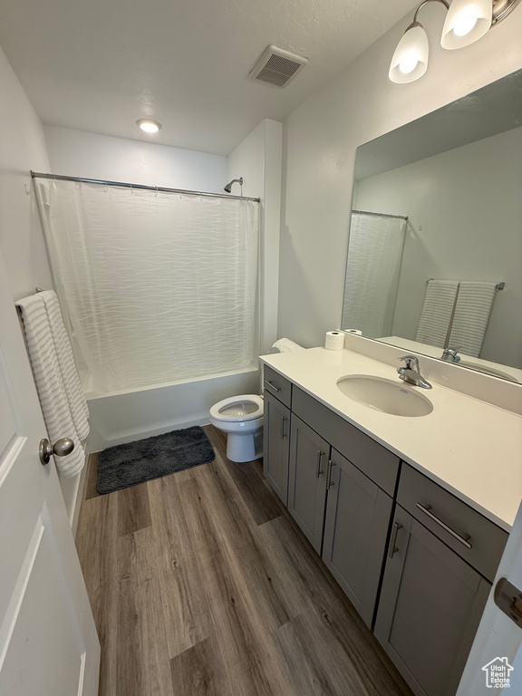 Bathroom with vanity, shower / tub combo with curtain, and wood finished floors
