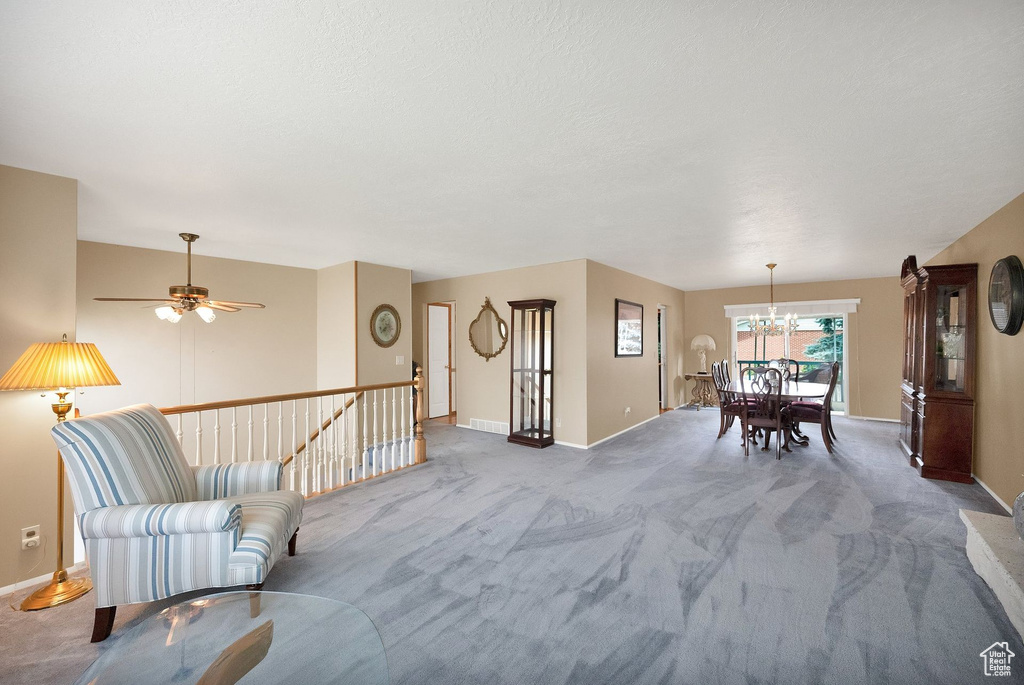 Carpeted living area with a chandelier and ceiling fan