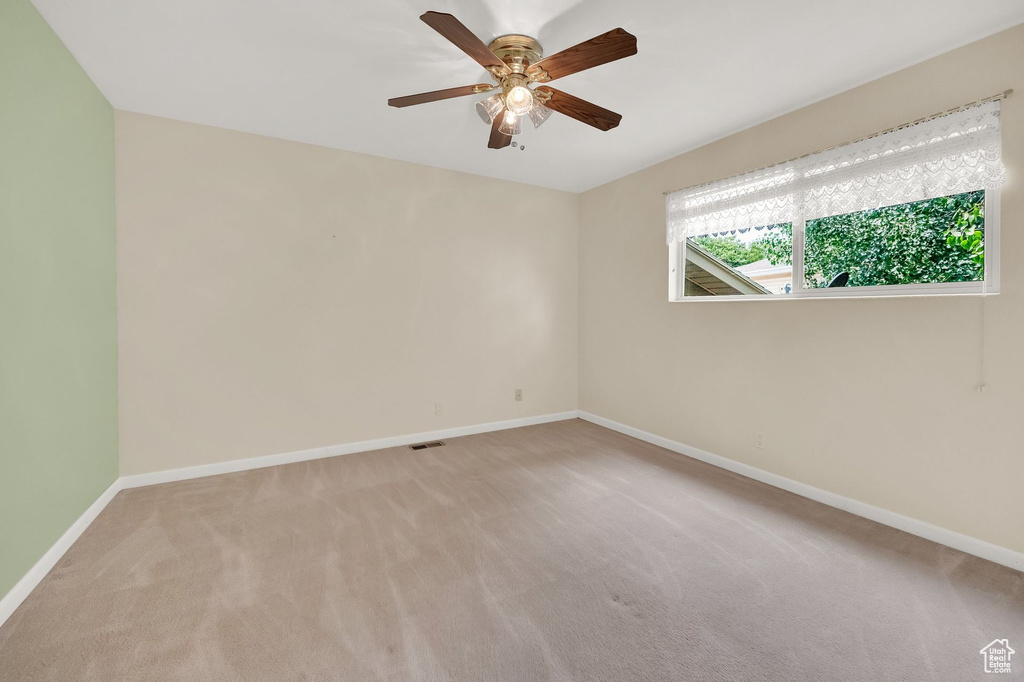 Empty room featuring carpet flooring and a ceiling fan