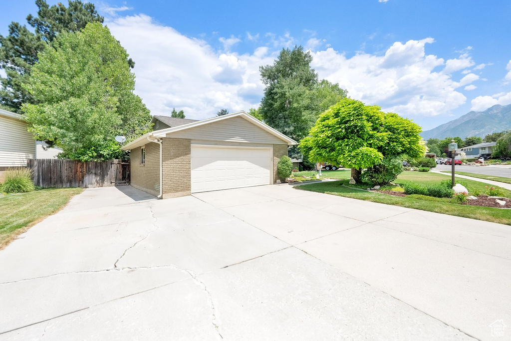 View of front of property featuring a mountain view, brick siding, driveway, and an attached garage