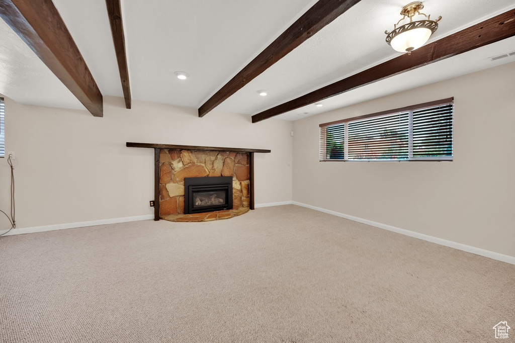 Unfurnished living room featuring carpet floors, beamed ceiling, a fireplace, and recessed lighting