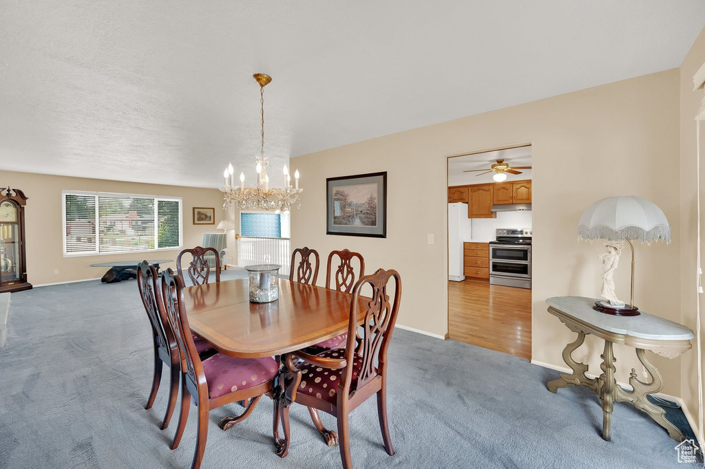 Carpeted dining room with a chandelier and ceiling fan