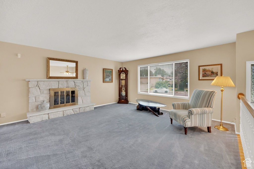 Carpeted living area featuring baseboards and a stone fireplace