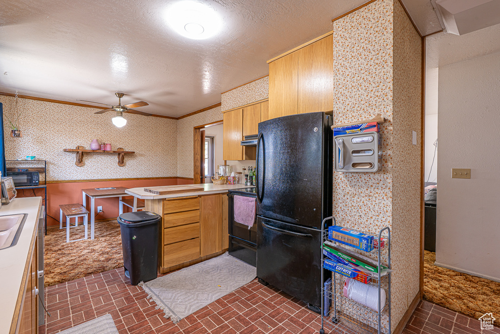 Kitchen featuring freestanding refrigerator, range, a peninsula, brick patterned floors, and ceiling fan