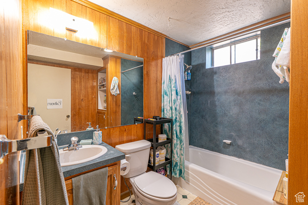 Bathroom with shower / bath combo with shower curtain, vanity, a textured ceiling, and wood walls