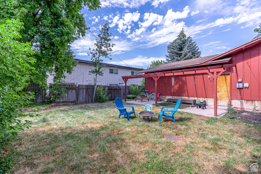Fenced backyard featuring a fire pit and a patio area