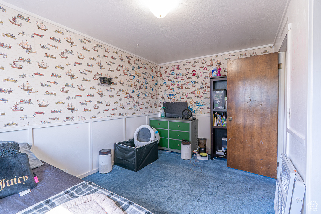 Bedroom featuring wallpapered walls, carpet floors, ornamental molding, and wainscoting