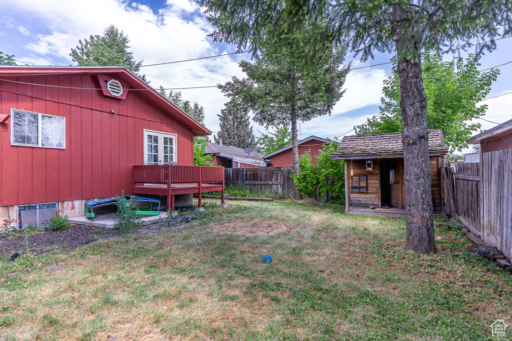 Fenced backyard featuring a storage unit and a wooden deck