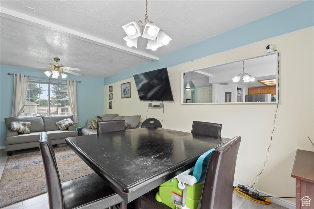 Dining room featuring a chandelier, beam ceiling, a textured ceiling, and a ceiling fan